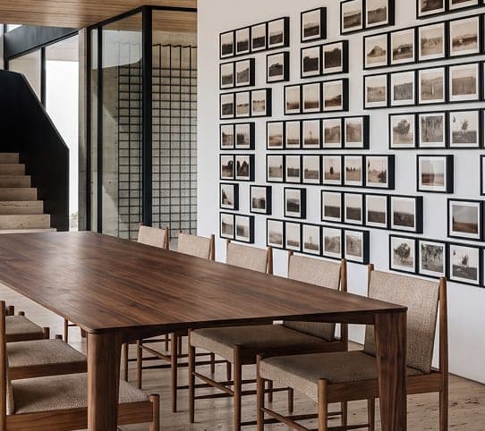 Sala de jantar com mesa de madeira maciça e parede de quadros, projeto de interiores da TRUÍV em Cruz, CE